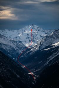 Photographie de montagne avec ligne directrice naturelle menant le regard vers un sommet enneigé, illustrée par une flèche rouge.