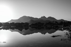 Photographie de montagne en noir et blanc avec le lac centré et le reflet dans l’eau, illustrant une composition symétrique volontairement recentrée.