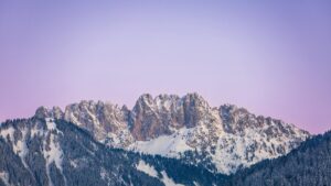Chaîne de montagnes enneigées capturée au téléobjectif avec une lumière rosée sur les sommets – Gastlosen, Suisse.