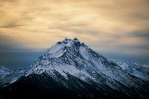 Sommet enneigé isolé au téléobjectif sous un ciel doré, capturant la puissance d’une montagne en hiver.