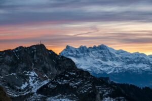 Massif enneigé des Dents du Midi au coucher du jour, photographié au téléobjectif avec effet de compression des plans et ciel coloré.