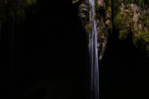 Chute d’eau en sous-bois photographiée en pleine journée contrastée