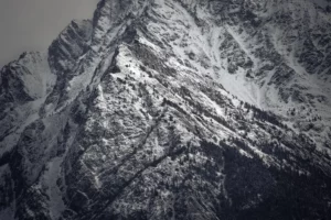 Montagne couverte de neige légèrement éclairée par une lumière diffuse qui met en valeur les textures rocheuses.