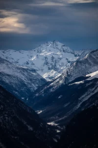 Vue prise en hauteur montrant une vallée enneigée et des montagnes lointaines
