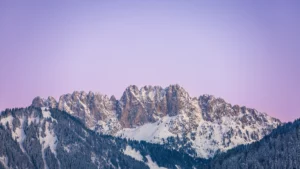Chaîne de montagnes enneigées au crépuscule, ciel rose et violet